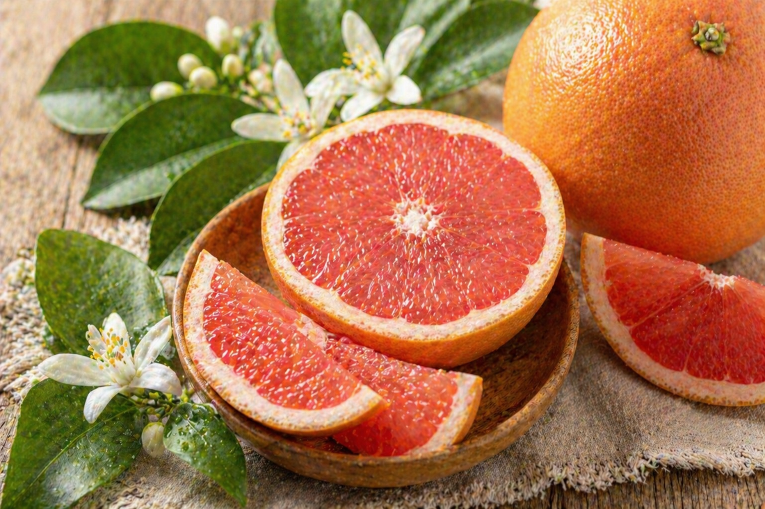 Frisches Duftbild mit rosa Grapefruit, Grapefruitscheiben und grünen Blättern auf natürlichem Hintergrund für ätherisches Grapefruitöl