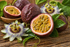 Tropisches Duftbild mit Passionsfrucht, geöffneter Maracuja und exotischen Blüten auf natürlichem Hintergrund für Passionfruit Fragrance Oil