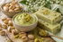Cremiges Duftbild mit Pistazien, gehackten Pistazien und weichen grünen Nuancen auf hellem Hintergrund für Pistachio Fragrance Oil
